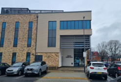 Image shows photo of the outside of the Hadrian Health Centre building, showing the front entrance and car park facilities.