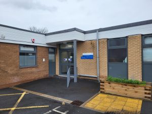 Image shows photo of the outside of the Shields Health Hub building, showing the front entrance and signage.